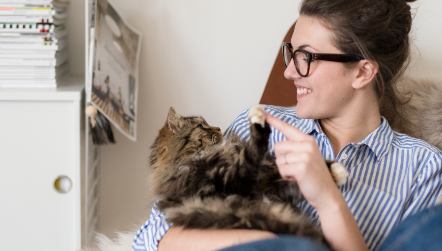 Naine istub ja puudutab sõrmega oma süles oleva kassi käppa